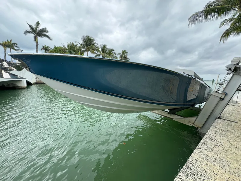 Slide: The Image of 2013 Nor-Tech 420 Monte Carlo boat on lift, surrounded by palm trees and water. - 5