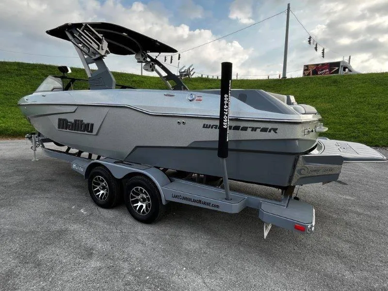 Slide: The Image of 2020 Malibu 25 LSV boat on trailer, parked outdoors under cloudy sky. - 4