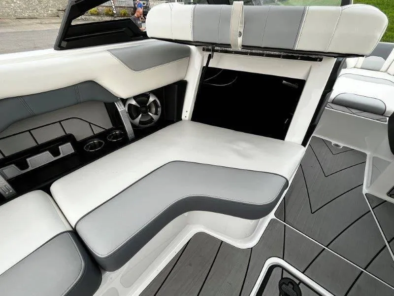 Slide: The Image of 2020 Malibu 25 LSV boat interior with gray and white seating and storage compartment. - 45