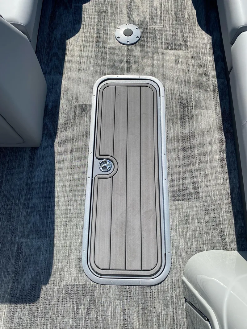 Slide: The Image of 2024 Ranger Reata 223C boat deck with storage hatch and gray flooring. - 10
