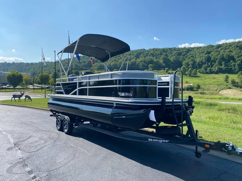 Slide: The Image of 2024 Ranger Reata 223C pontoon boat on trailer, parked in scenic outdoor setting. - 4