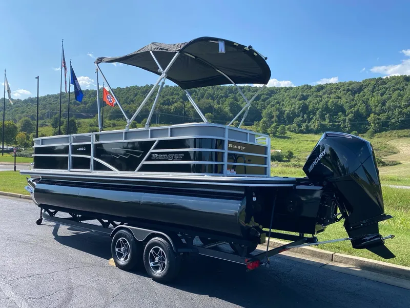 Slide: The Image of 2024 Ranger Reata 223C pontoon boat on trailer, parked outdoors under clear sky. - 6