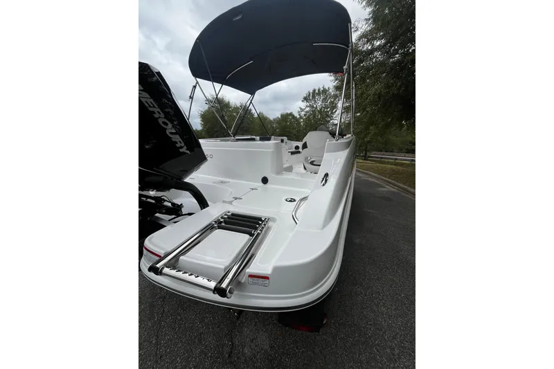 Slide: The Image of 2024 Tahoe 2150 boat with canopy and Mercury engine, parked on a road. - 4