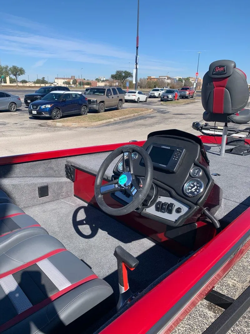 Slide: The Image of 2024 Ranger RT188 boat interior with steering wheel and seating, parked outdoors. - 2