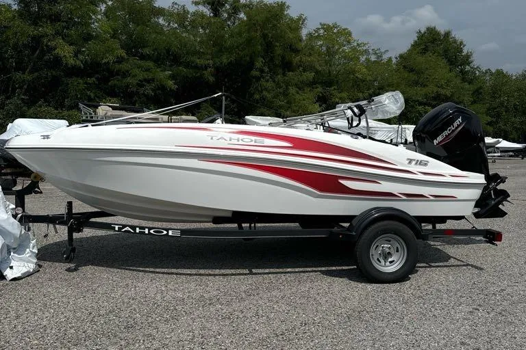 Slide: The Image of 2024 Tahoe T16 boat with red accents on a trailer, parked outdoors. - 0