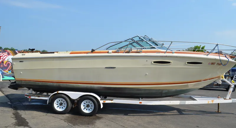Slide: The Image of 1981 Sea Ray V240 boat on trailer, beige with orange trim, parked outdoors. - 1