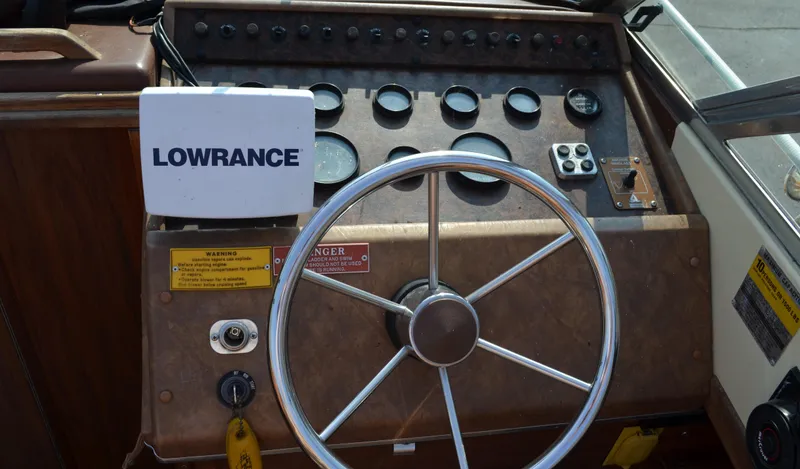 Slide: The Image of 1981 Sea Ray V240 boat dashboard with steering wheel and Lowrance navigation system. - 11