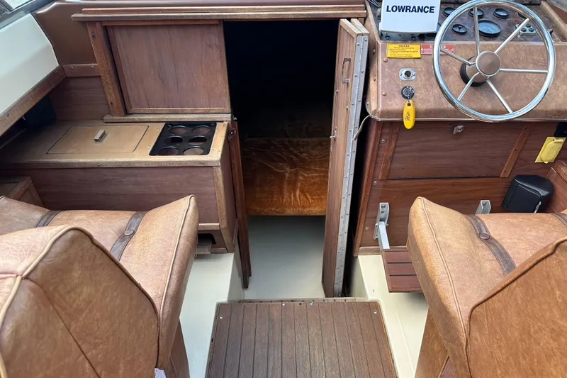Slide: The Image of 1981 Sea Ray V240 boat interior with wood paneling and steering wheel. - 13