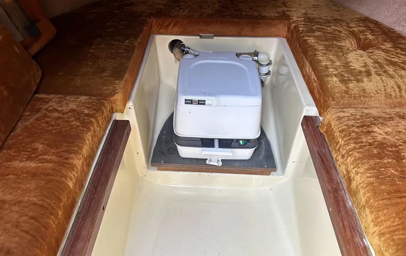 Slide: The Image of 1981 Sea Ray V240 cabin with portable toilet and brown seating. - 15