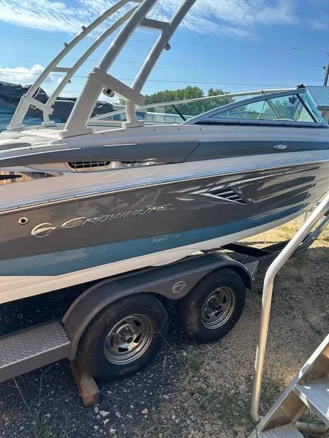 Slide: The Image of 2021 Crownline 220SS boat on trailer, side view, under clear blue sky. - 2