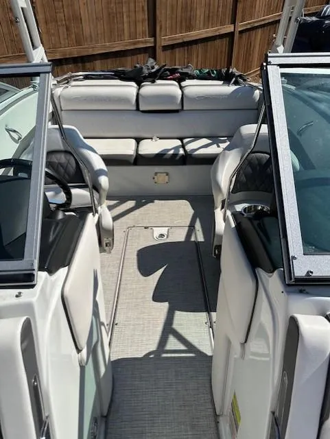 Slide: The Image of 2021 Crownline 220SS boat interior with seating and windshield, parked outdoors. - 7