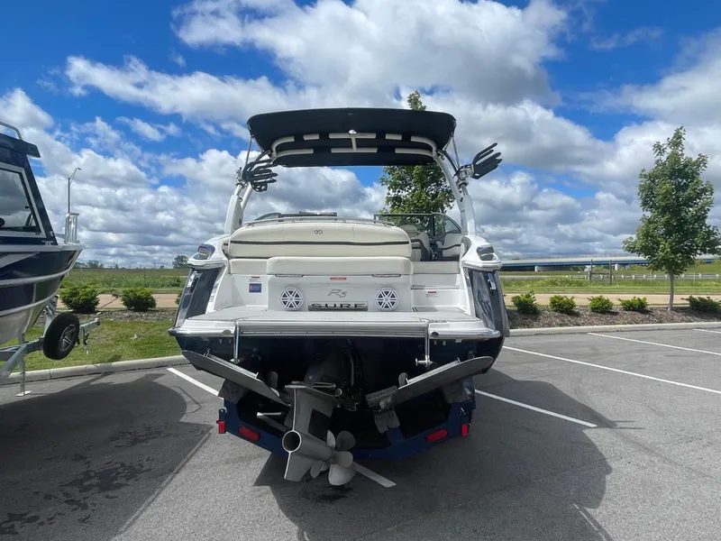 Slide: The Image of 2021 Cobalt R5 Surf boat parked, rear view, under a partly cloudy sky. - 4