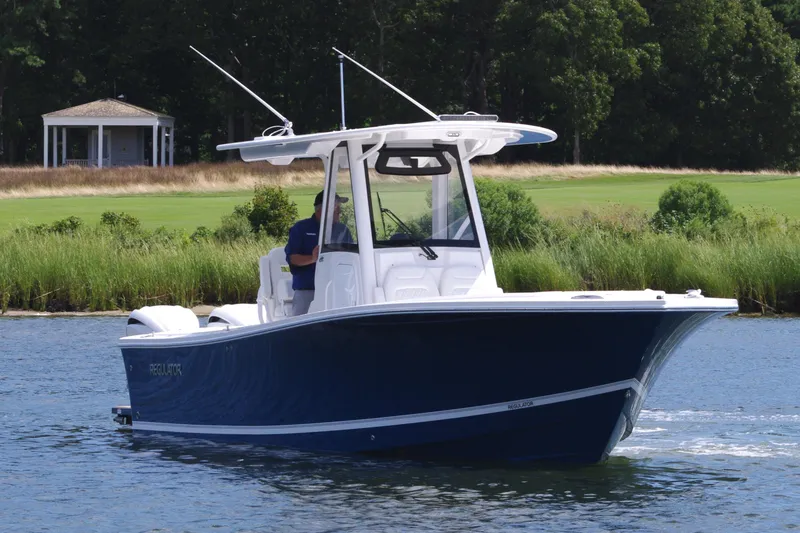 Slide: The Image of 2025 Regulator 28 boat cruising on a calm river with lush greenery. - 10