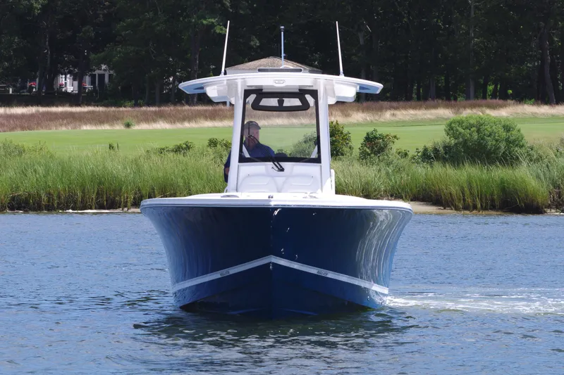 Slide: The Image of 2025 Regulator 28 boat cruising on a calm lake with lush greenery. - 11