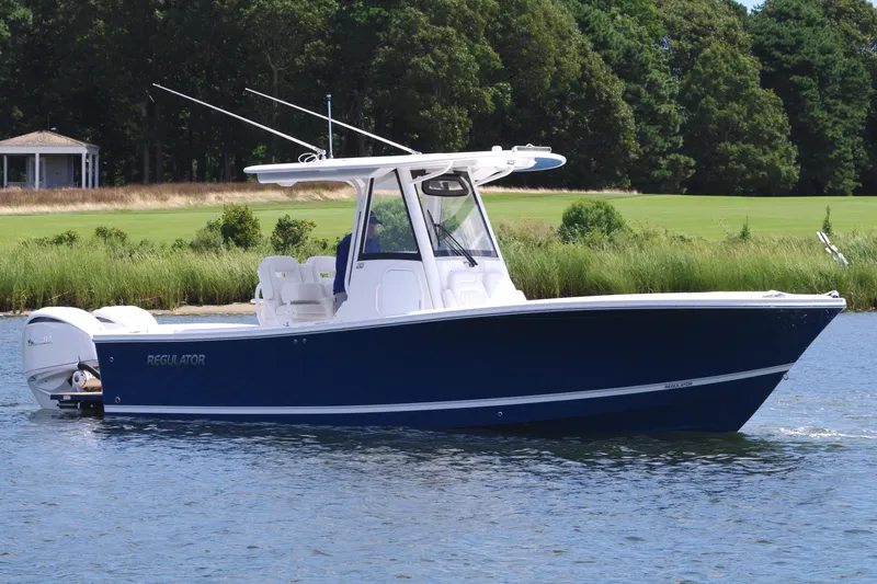 Slide: The Image of 2025 Regulator 28 boat on a calm lake with lush greenery in the background. - 9