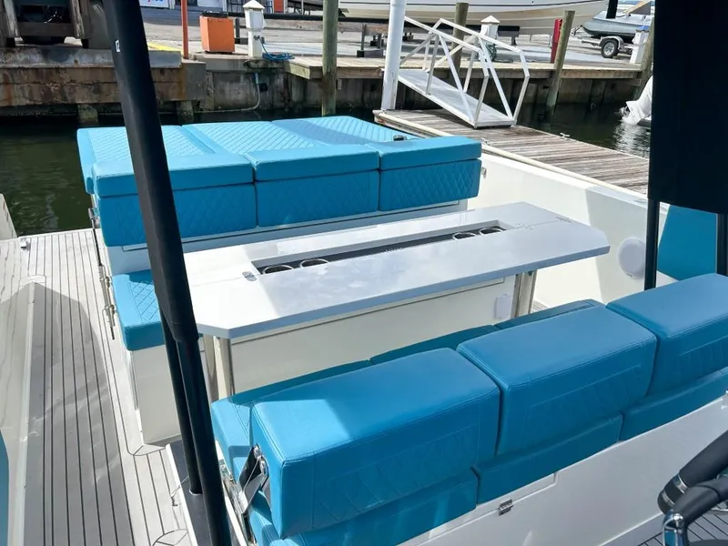 Slide: The Image of 2023 De Antonio Yachts D28 Open with blue seating and sleek design at a marina. - 16