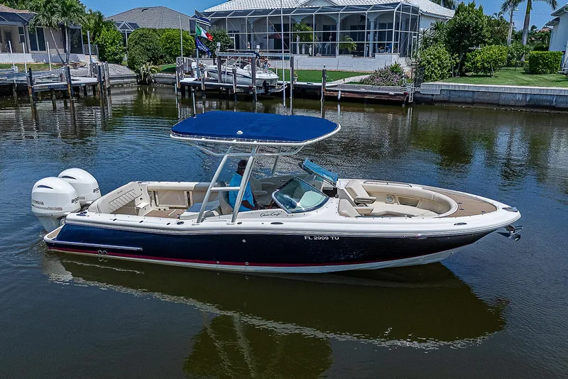 The Image of 2018 Chris-Craft Calypso 26 boat on calm water, featuring a sleek design and blue canopy. - 0