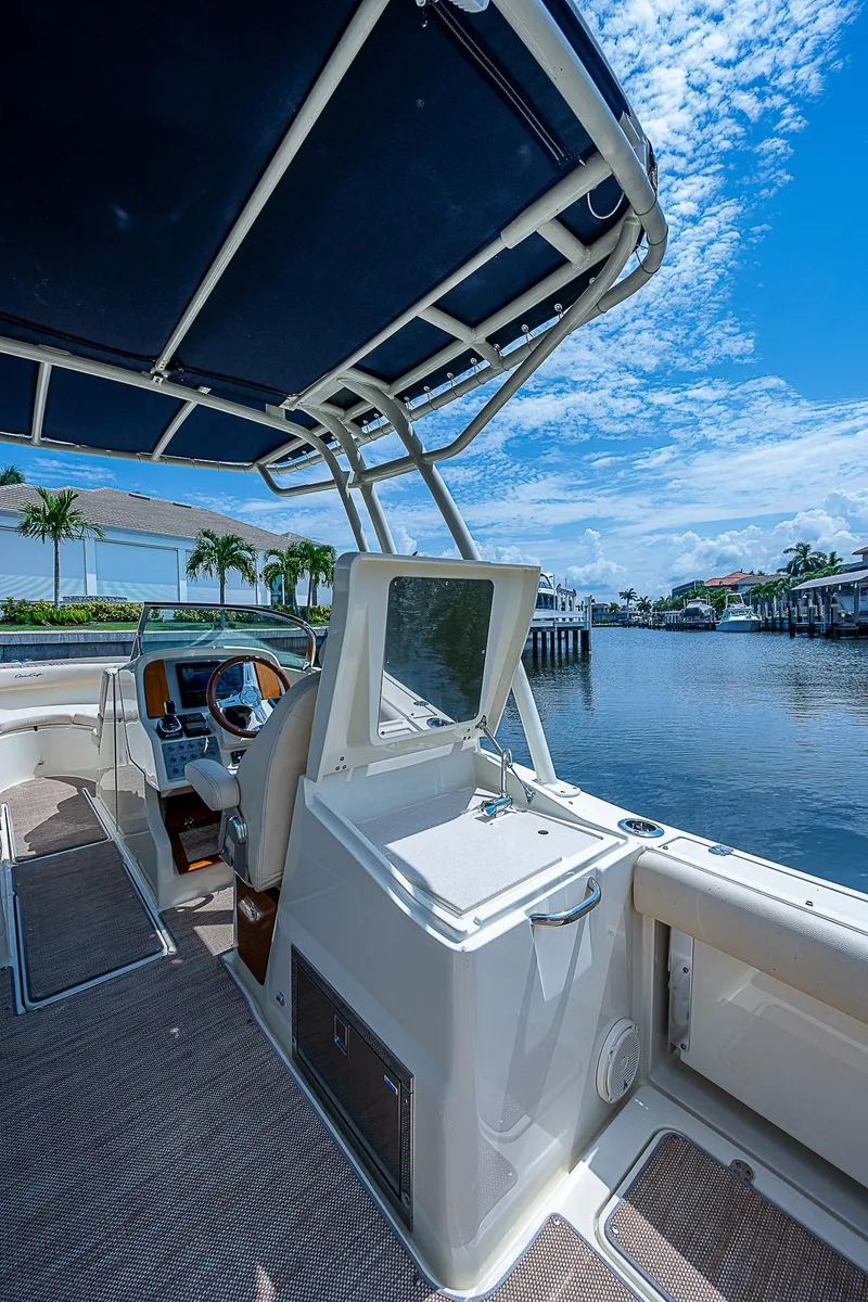 Slide: The Image of 2018 Chris-Craft Calypso 26 boat interior with waterfront view, featuring sleek design and canopy. - 10