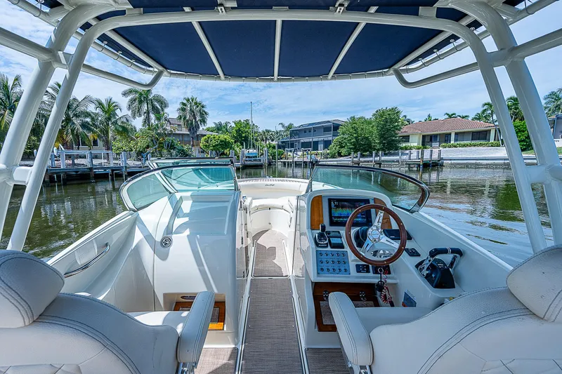 Slide: The Image of 2018 Chris-Craft Calypso 26 boat interior with helm, seats, and waterfront view. - 20