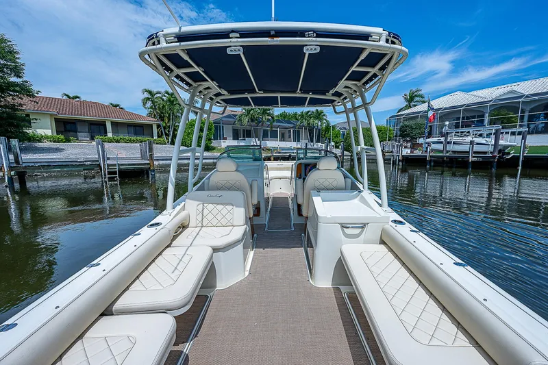 Slide: The Image of 2018 Chris-Craft Calypso 26 boat with spacious seating and canopy, docked by waterfront homes. - 9
