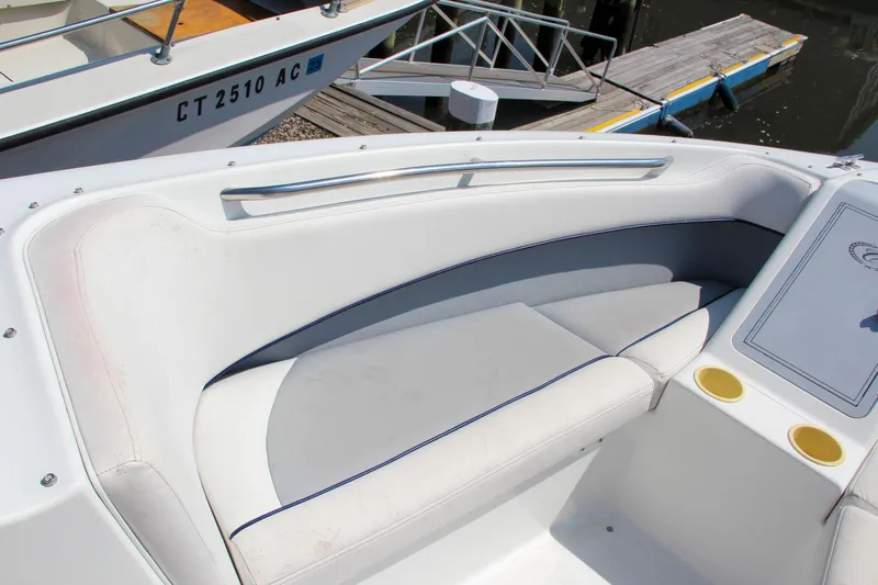 Slide: The Image of 1996 Cobalt 220 boat interior with white seating and cup holders at a dock. - 26