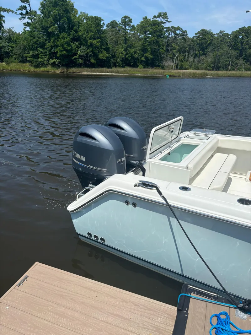 Slide: The Image of 2014 Sea Hunt Game Fish 27 boat with dual Yamaha engines docked on a calm lake. - 2