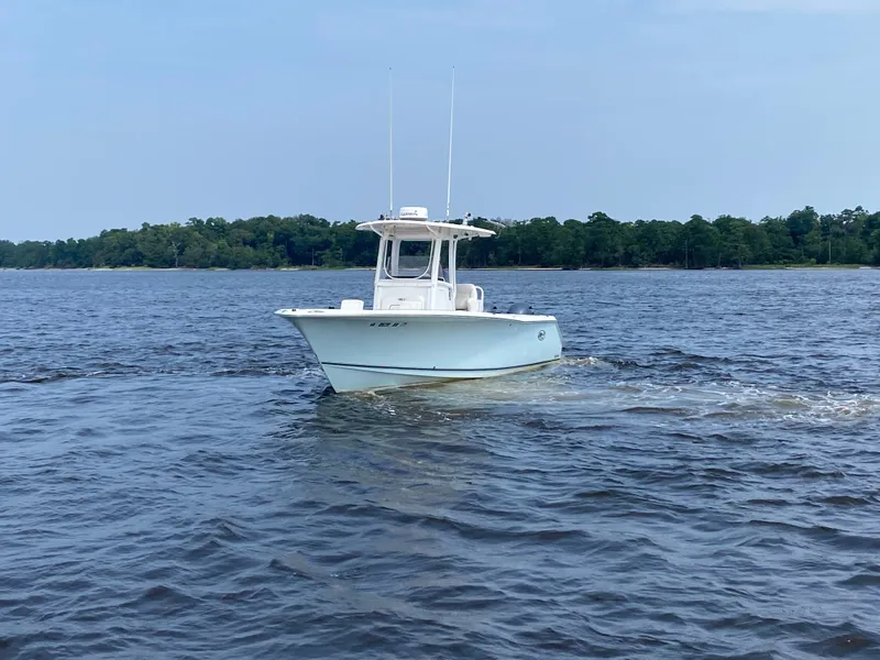 Slide: The Image of 2014 Sea Hunt Game Fish 27 boat on calm water, forested shoreline in background. - 9