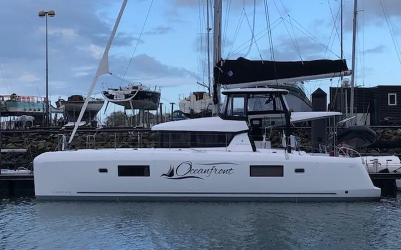The Image of 2019 Lagoon 42 catamaran docked in marina, featuring sleek design and "Oceanfront" branding. - 0