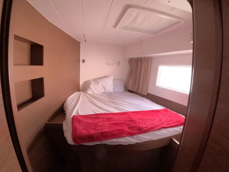 Slide: The Image of Cozy cabin interior of 2019 Lagoon 42 catamaran with bed and window. - 30