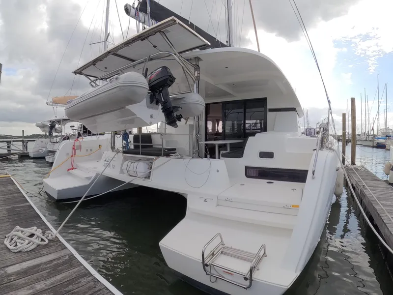Slide: The Image of 2019 Lagoon 42 catamaran docked, featuring spacious deck and mounted dinghy. - 38