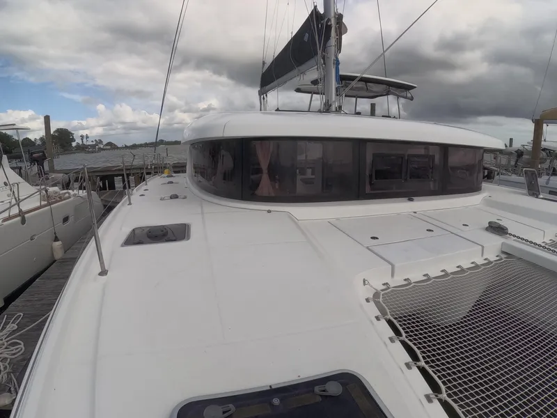 Slide: The Image of 2019 Lagoon 42 catamaran docked, featuring sleek design and spacious deck under cloudy skies. - 40