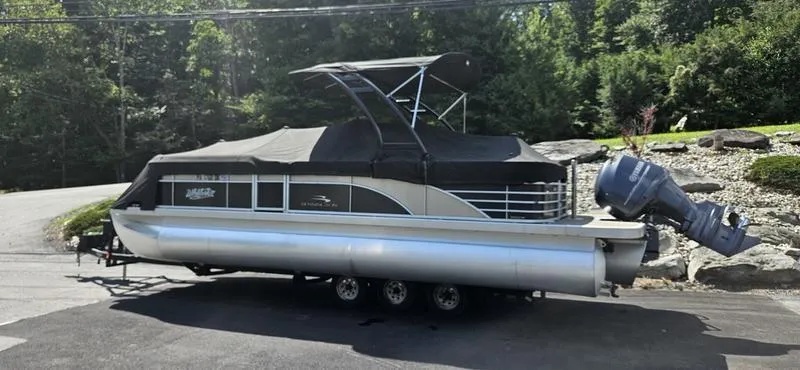Slide: The Image of 2013 Bennington 2375 GCW pontoon boat with canopy on a trailer, parked outdoors. - 3