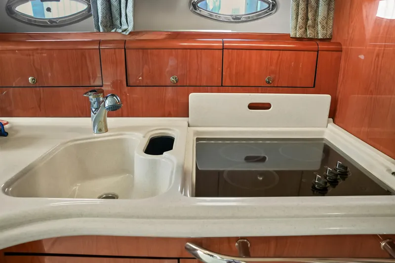 Slide: The Image of 2001 Sea Ray 510 Sundancer kitchen with sink and stovetop, wooden cabinetry. - 46