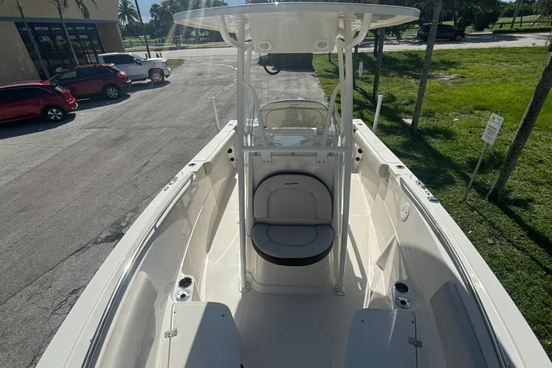 Slide: The Image of 2023 Sailfish 220 CC boat interior with seating and console, parked outdoors. - 5
