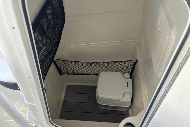 Slide: The Image of 2023 Sailfish 220 CC boat interior with portable toilet and storage net. - 8