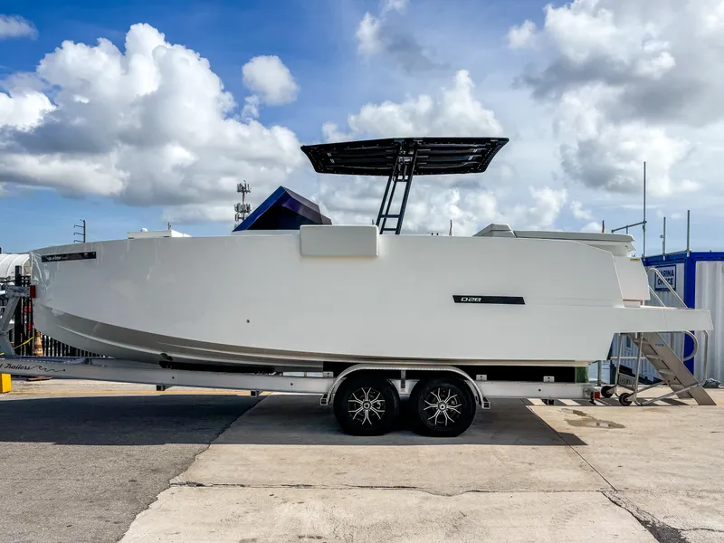 Slide: The Image of 2024 De Antonio Yachts D28 Open on trailer, sleek design, under cloudy sky. - 1