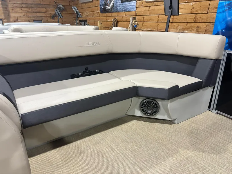 Slide: The Image of 2025 Harris CRUISER 230 SL boat interior with beige and gray seating, speaker, and wooden wall background. - 2