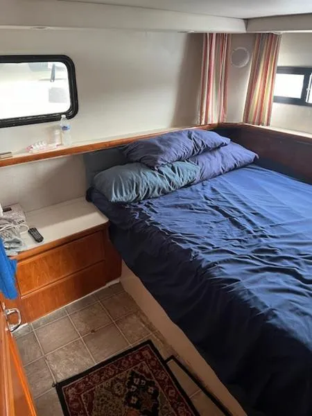 Slide: The Image of Cozy bedroom in 1991 Carver 33 Aft Cabin yacht with blue bedding and wood accents. - 7