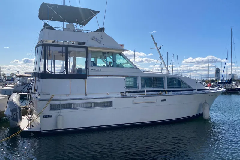 Slide: The Image of 1977 Bertram 42 Motor Yacht docked in a marina under a clear blue sky. - 2