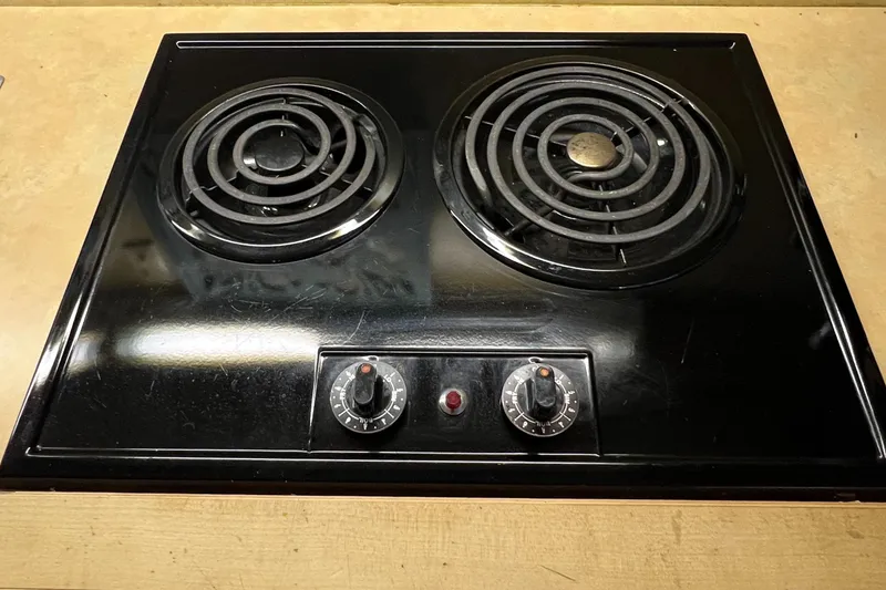 Slide: The Image of Black electric stove with two coil burners and control knobs on a wooden surface. - 20