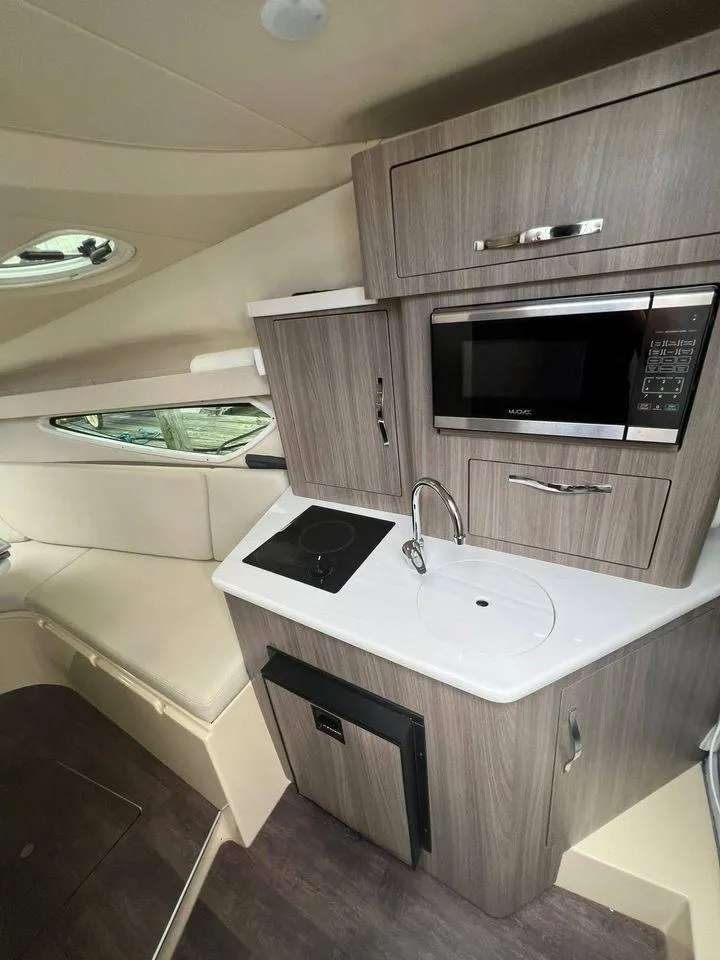 Slide: The Image of 2021 Regal 28 Express boat interior kitchen with microwave, sink, and stove. - 6