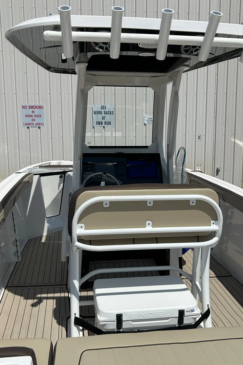 Slide: The Image of 2024 Yamaha Boats 252 FSH Sport, center console view, rod holders, beige seating, docked. - 8