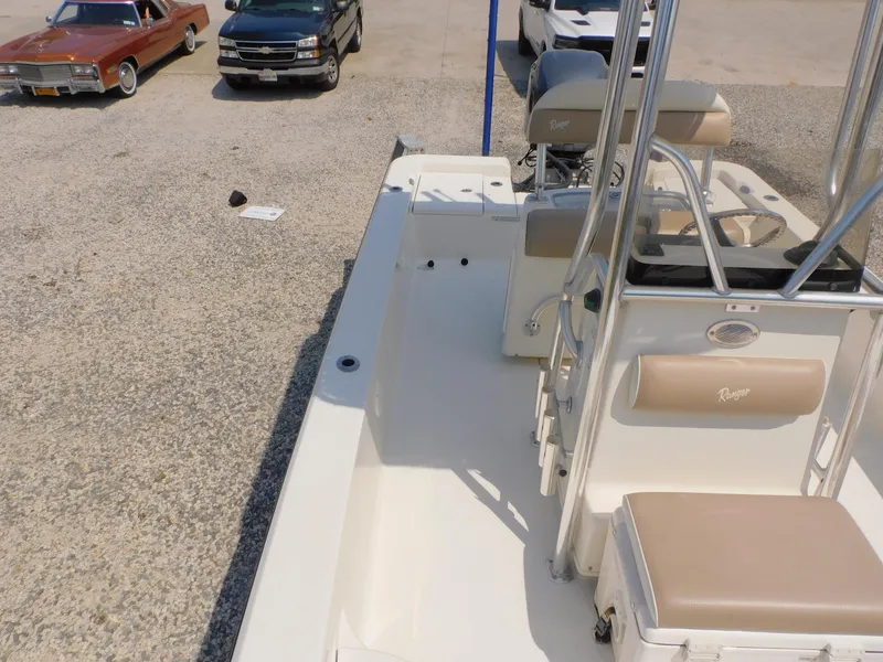 Slide: The Image of 2009 Ranger 2200 Bay Ranger boat interior with seating and console, parked near classic cars. - 30