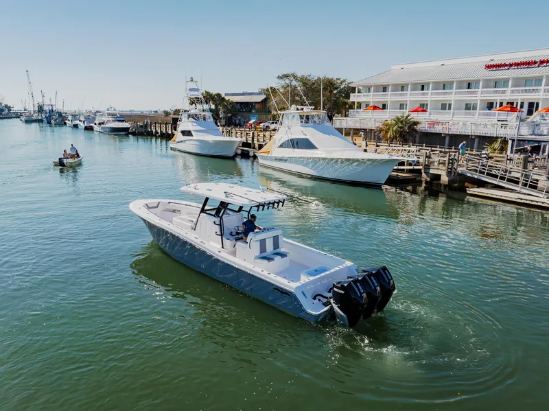 Slide: The Image of 2025 Invincible 36 Open Fisherman boat cruising near a marina with other vessels. - 37