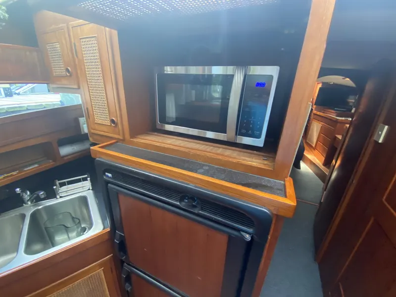 Slide: The Image of 1986 Midnight Lace 52 Flybridge kitchen with microwave, sink, and wooden cabinetry. - 15