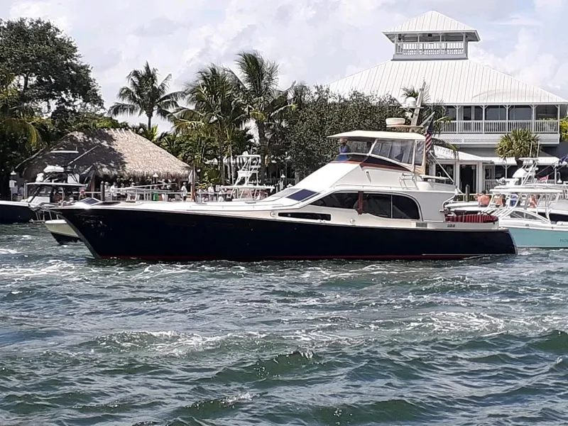 Slide: The Image of 1986 Midnight Lace 52 Flybridge yacht cruising near a tropical marina with palm trees. - 2