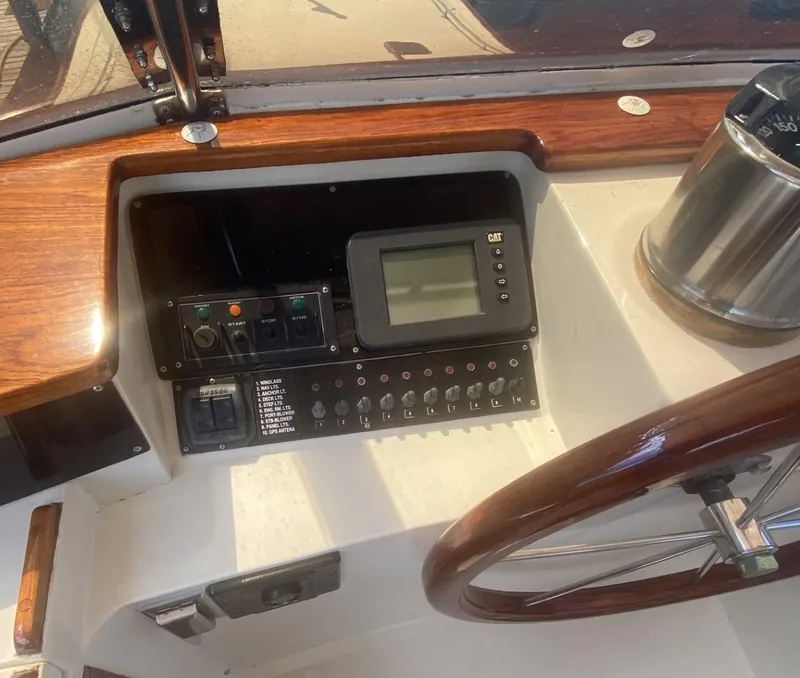 Slide: The Image of 1986 Midnight Lace 52 Flybridge helm with wooden steering wheel and control panel. - 23