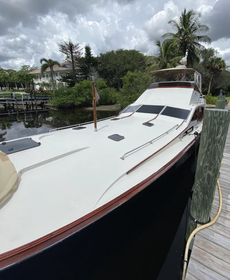 Slide: The Image of 1986 Midnight Lace 52 Flybridge yacht docked by lush greenery under cloudy skies. - 34
