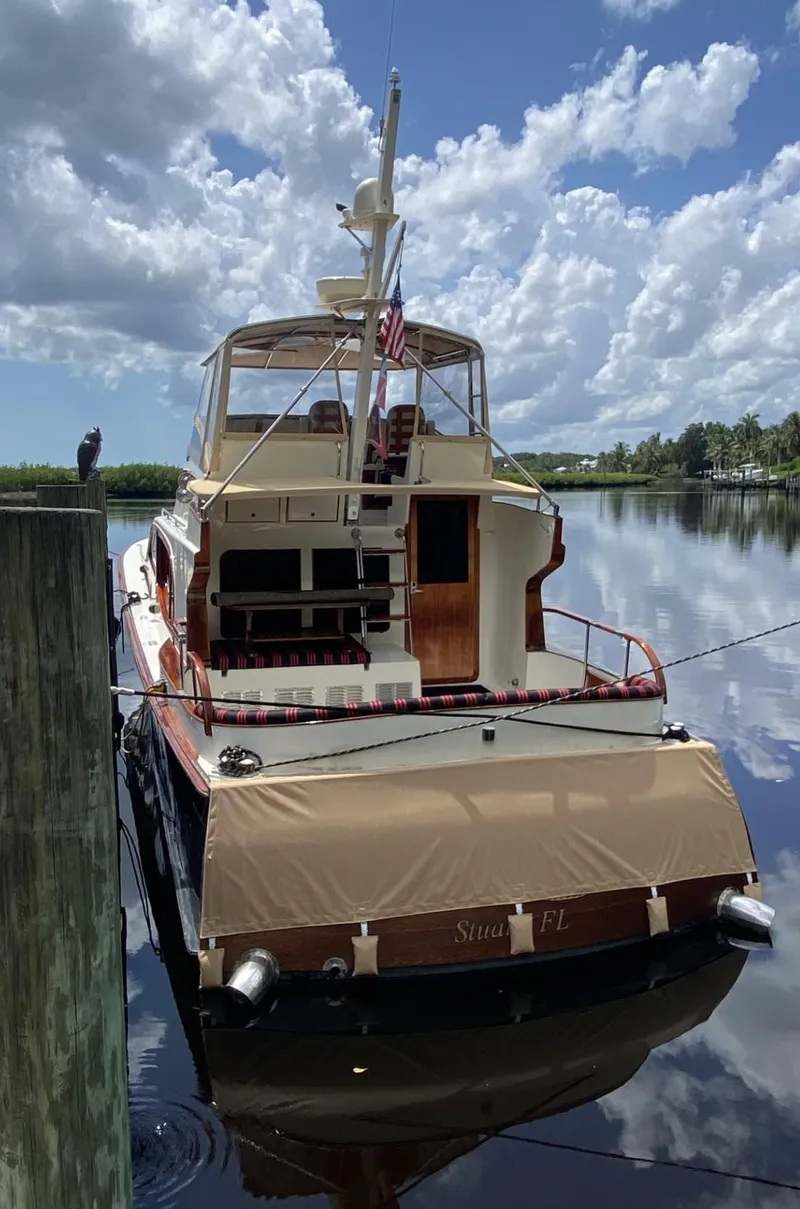 Slide: The Image of 1986 Midnight Lace 52 Flybridge yacht docked on a calm, reflective waterway. - 7