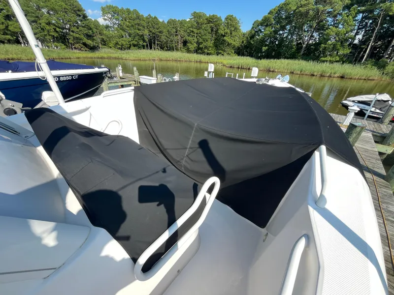 Slide: The Image of 2013 Everglades 295 Center Console boat with black cover docked by a lush shoreline. - 11